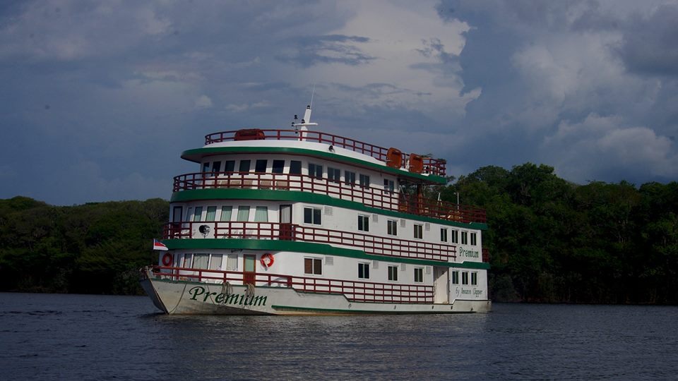 Barco turístico navegando no Rio Amazonas com vegetação ao fundo